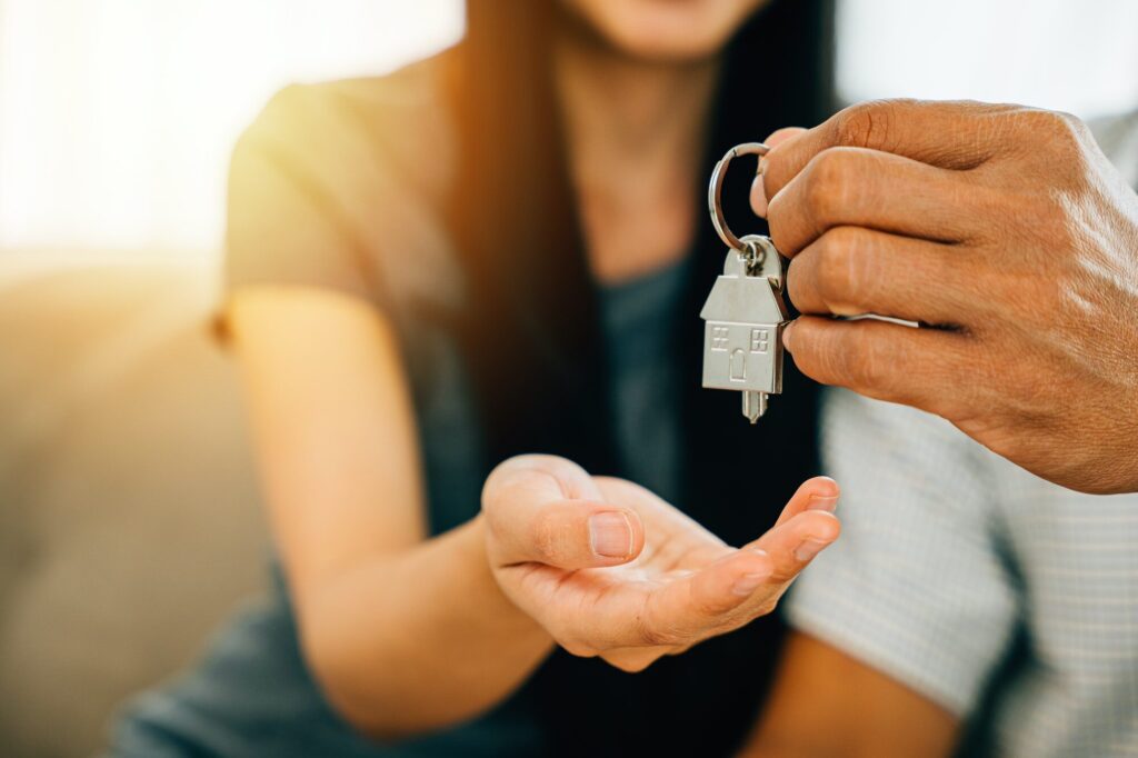 A delighted couple celebrates new homeownership displaying keys to their house