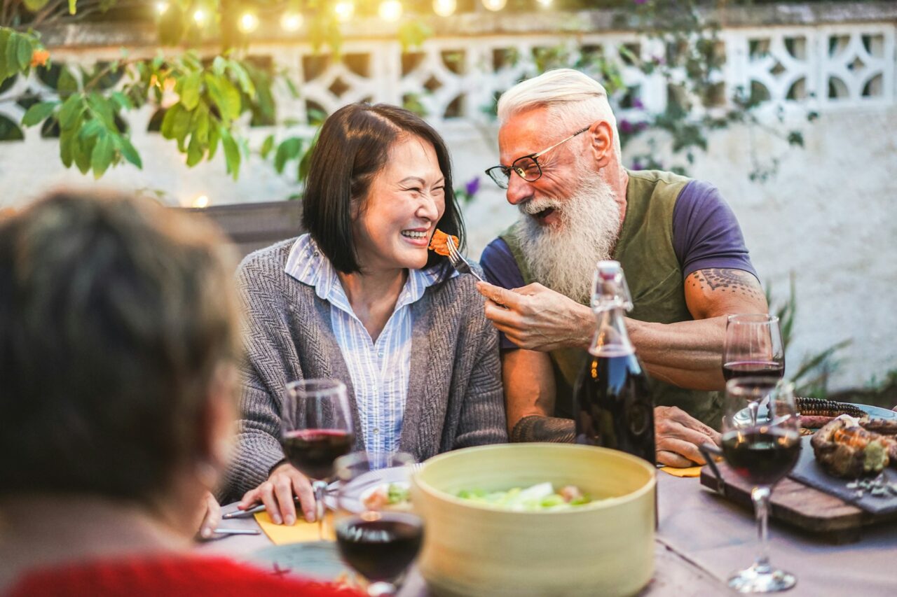 Happy senior people having fun at barbecue dinner - Multiracial mature friends eating at bbq meal