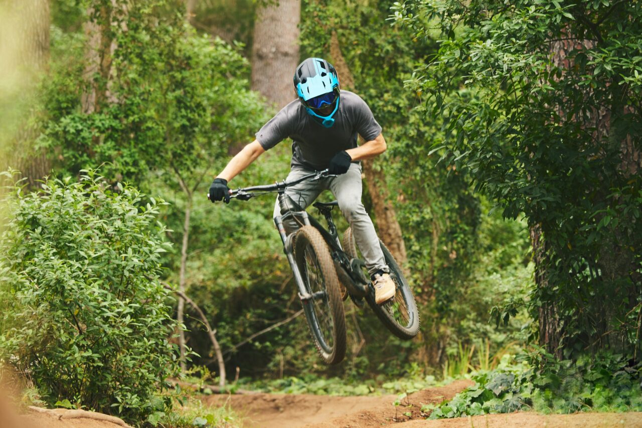 Mountain bike, man and jump in nature for cycling competition, action or adventure of extreme sport