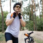 Portrait of male mountain biker wearing bicycle helmet in the forest on a sunny day.