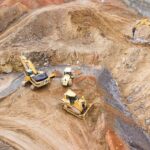 top view photography of four heavy equipment on quarry at daytime