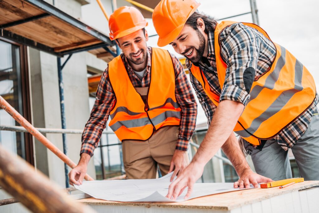 handsome smiling builders looking at construction plan