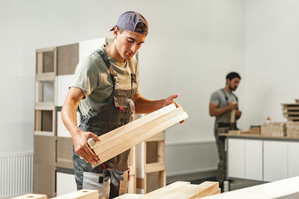 Young carpenter man looking and choosing wood plank at workshop in carpenter wood factory