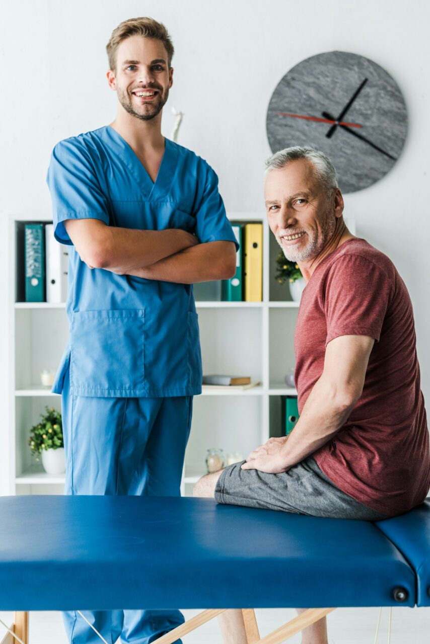 cheerful doctor standing with crossed arms near happy patient