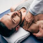 chiropractor massaging shoulder of man on Massage Table in hospital