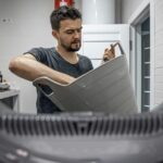 A man loads laundry into the washing machine, inside view.