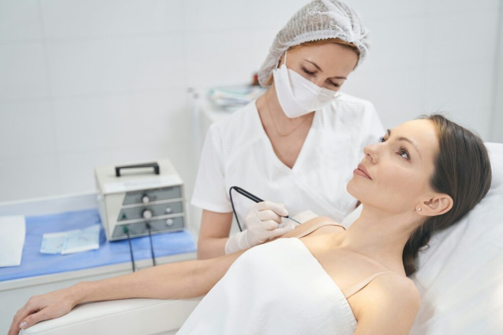Doctor performing laser mole removal procedure in beauty clinic