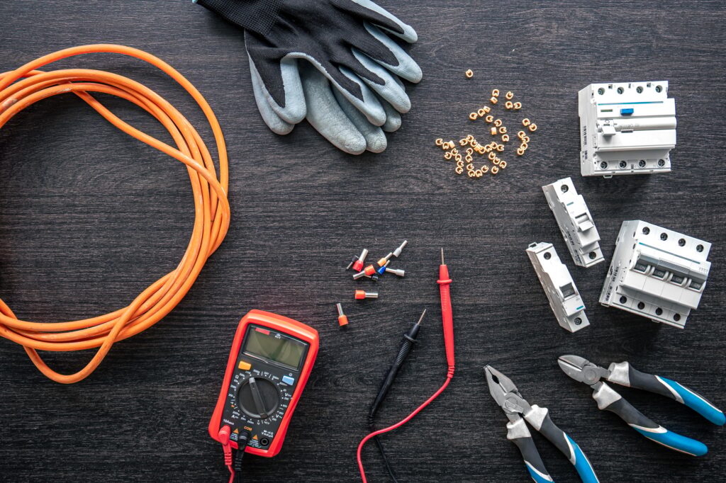 Different electrical tools on wooden background, flat lay.