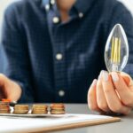 Female hand holding a light bulb above the table