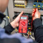 Worker measuring and repairing an electrical system panel
