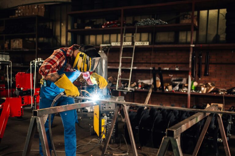 Man welding metal with welding machine while wearing a protective gear