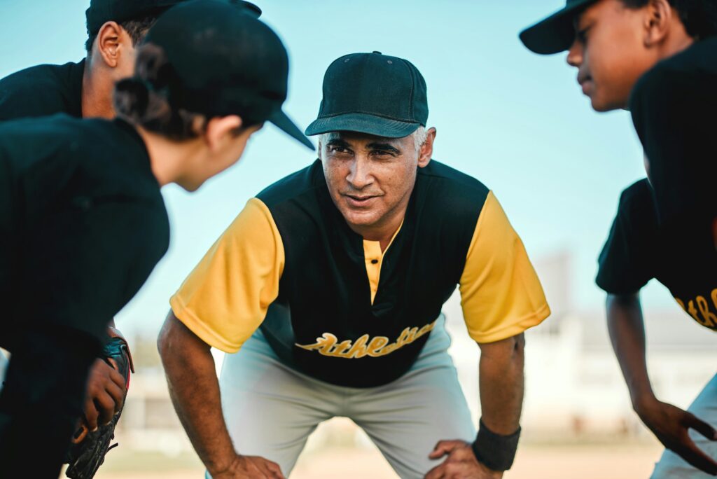 Keep doing what you are doing. Shot of a baseball coach talking to his team while out on the pitch.