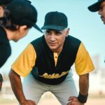 Keep doing what you are doing. Shot of a baseball coach talking to his team while out on the pitch.
