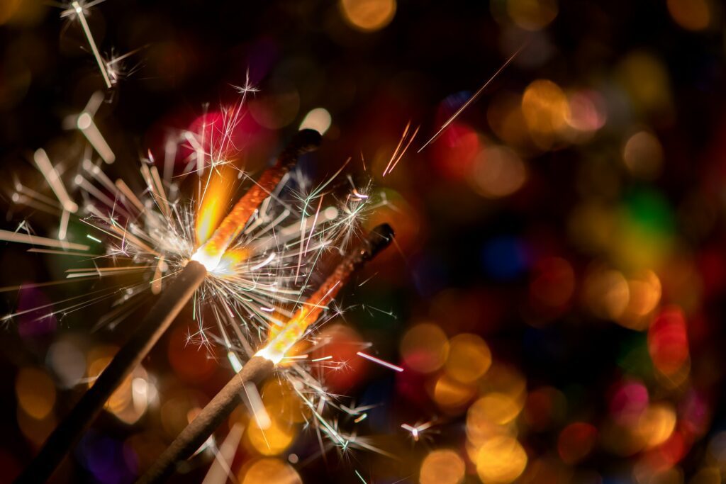 Glowing holiday sparkling hand fireworks, shining fire flame. Christmas light. Abstract background