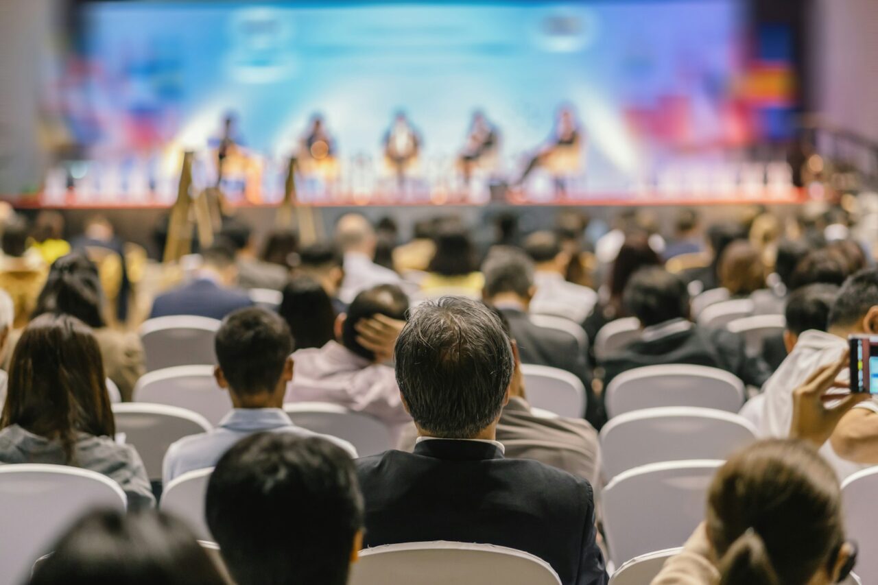 Rear view of Audience listening Speakers on the stage in the conference hall or seminar meeting