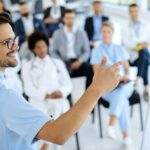Young happy doctor holding healthcare seminar in convention center.