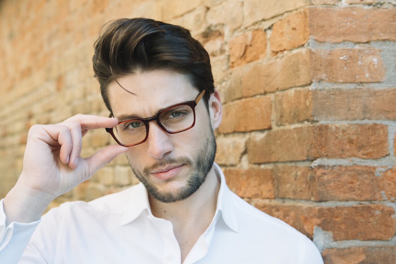 Portrait of a man wearing glasses at brick wall