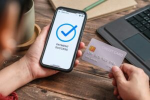 close up woman hand payment by credit card shopping online success on mobile app at home