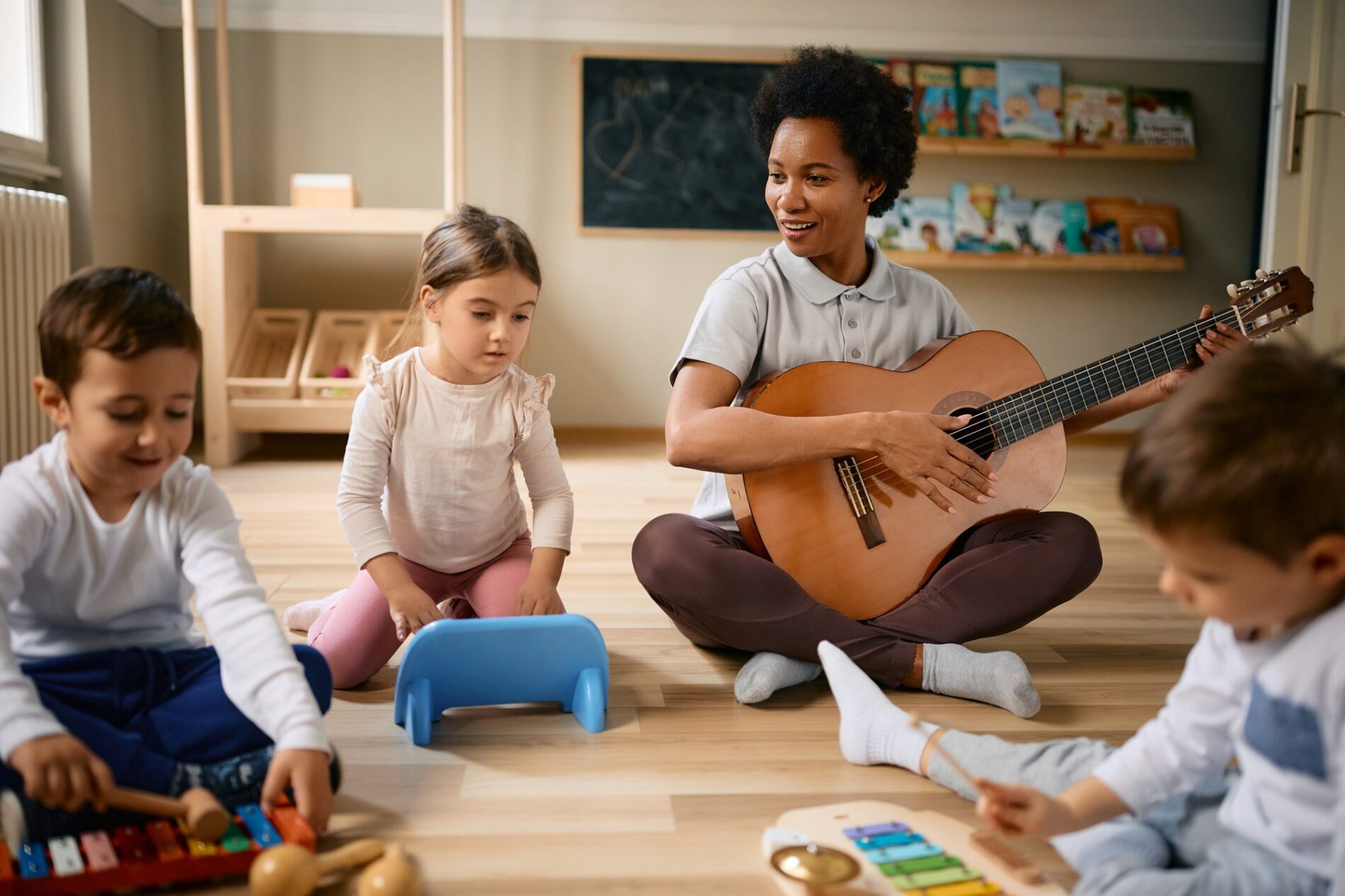African American teacher and group of kids having fun on music class at kindergarten.