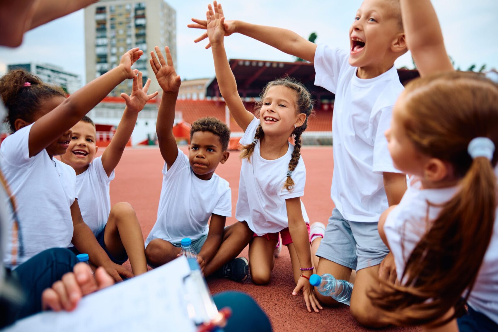 Cheerful group of kids having fun during sports training at the stadium.