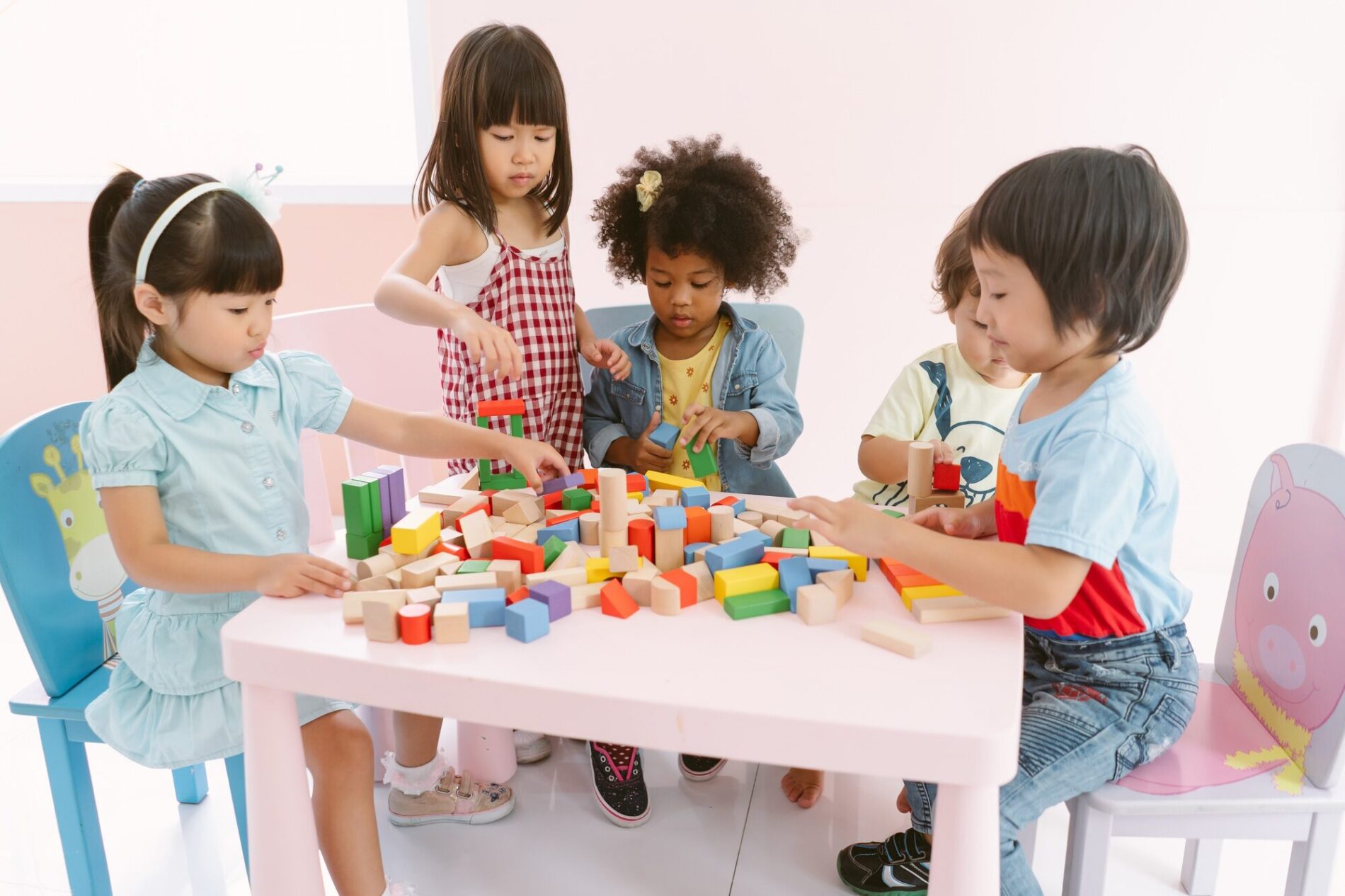 Group of diversity kids playing with colorful blocks on table in class at the kindergarten.