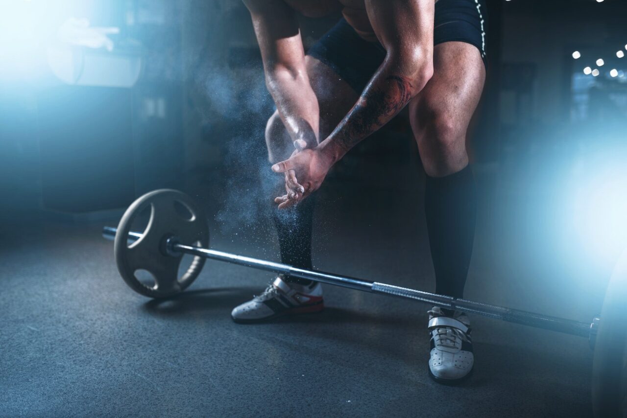 Athlete hands in powder and talc, barbell exercise