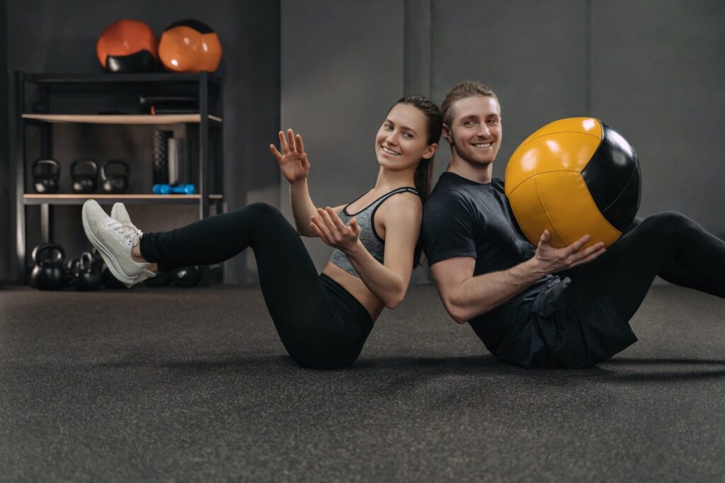 Crossfit couple exercising together with a ball