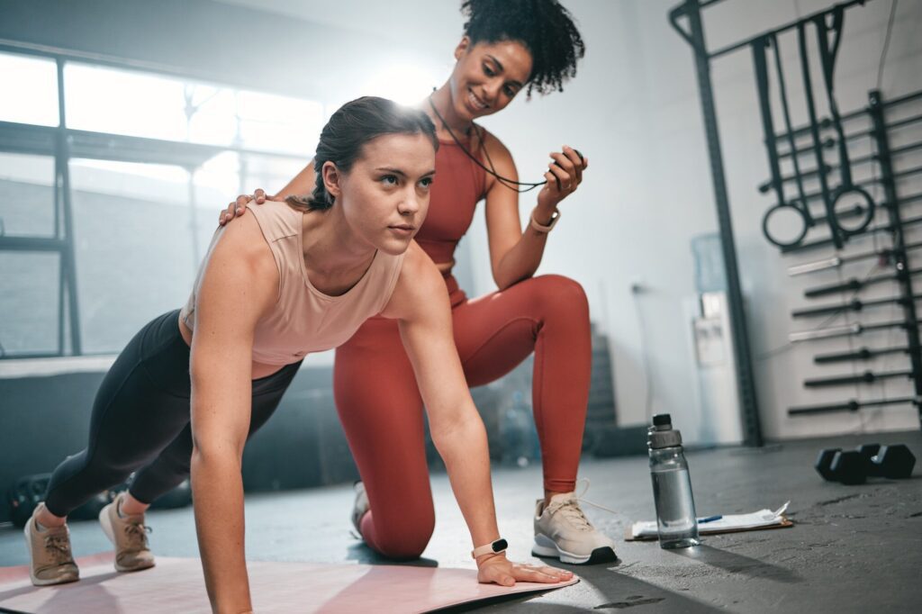 Personal trainer, fitness and stopwatch with a black woman coaching a client in a gym during her wo