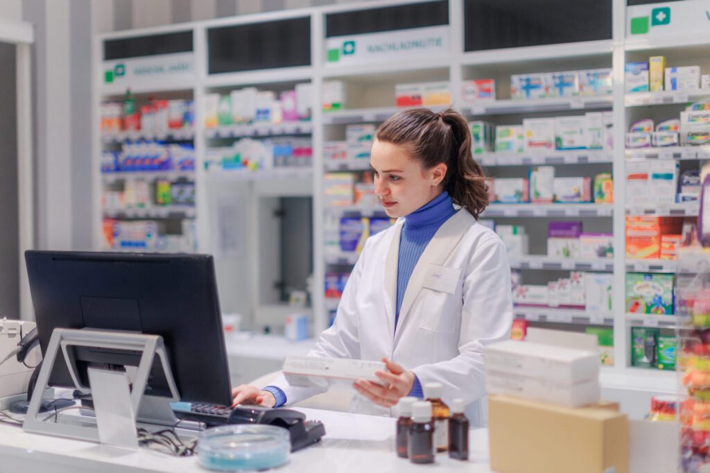 Portrait of young pharmacist selling medication in pharmacy.