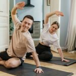 Couple joyfully stretching on yoga mats at home, sharing a moment of fitness and wellness