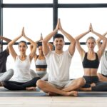Wellbeing Concept. Happy multicultural people practicing group yoga in modern studio