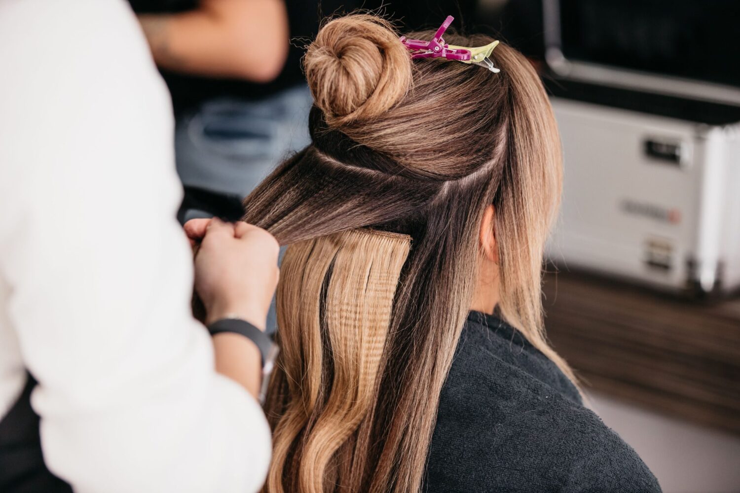 Young female with long wavy hair styling her locks using a straightener